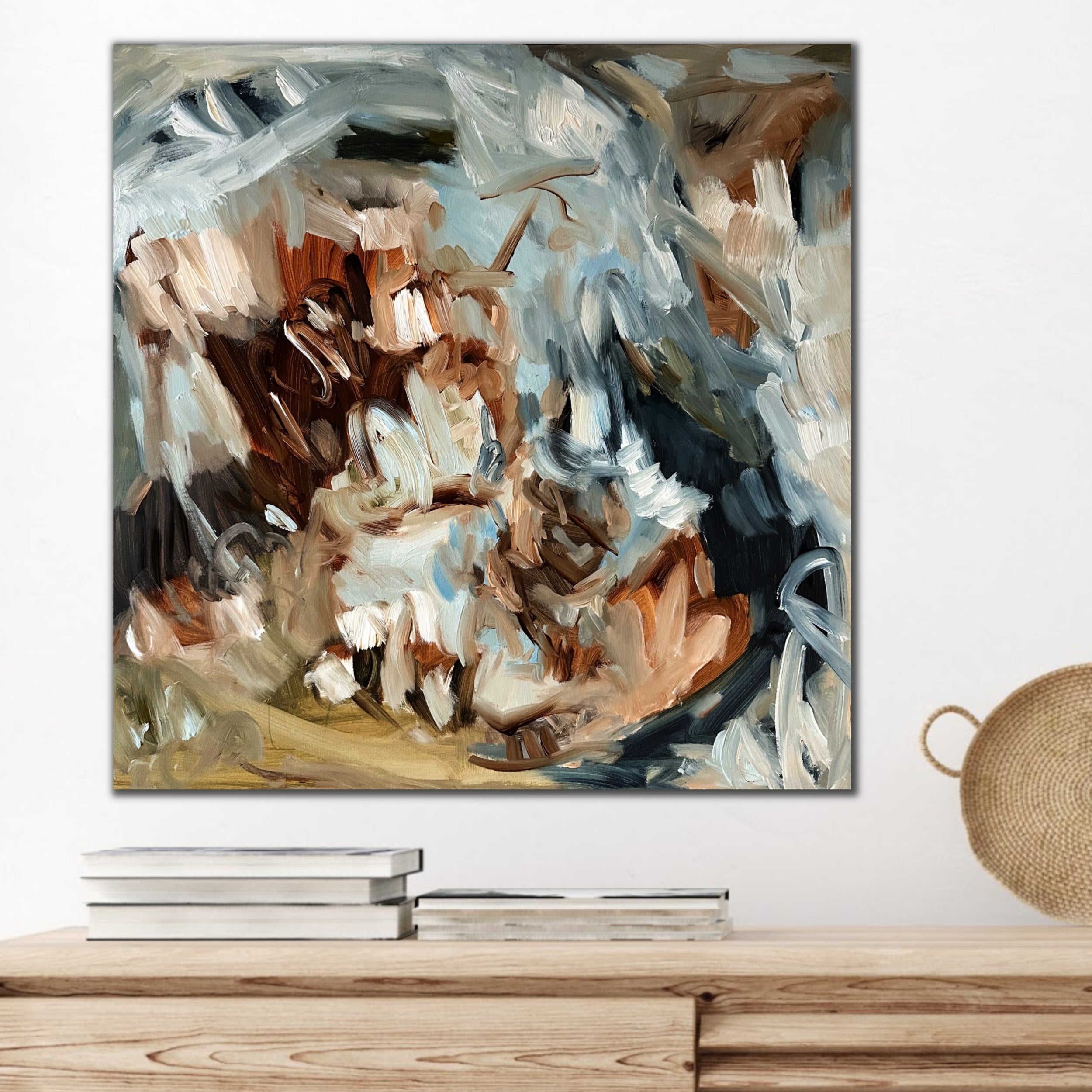Abstract painting hanging on a wall above a wooden cabinet