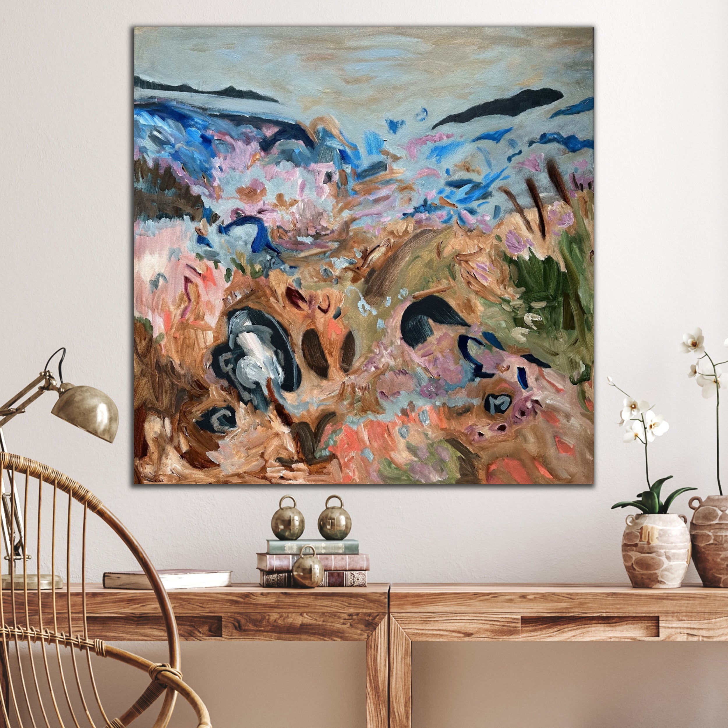 Square landscape painting in multi-colour hanging on wall in room with natural neutral interior