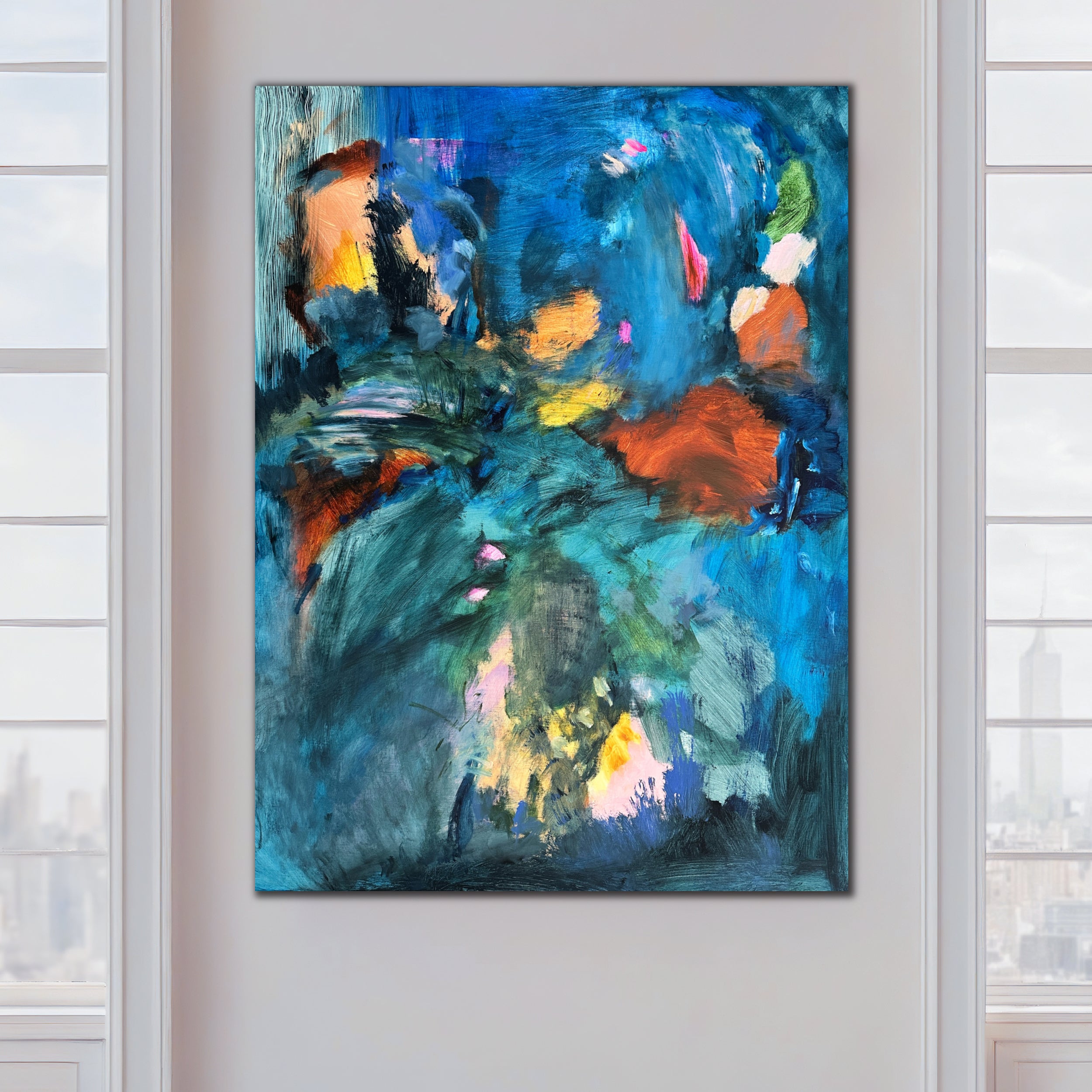 Abstract expressionist painting in blue and complimentary vibrant colors hanging on an interior wall