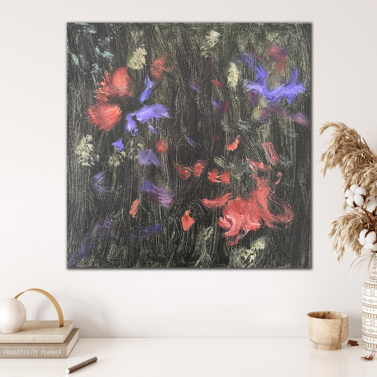 Abstract artwork in gestural, expressive painting style hanging on wall in home with decorative accessories in natural finishes.