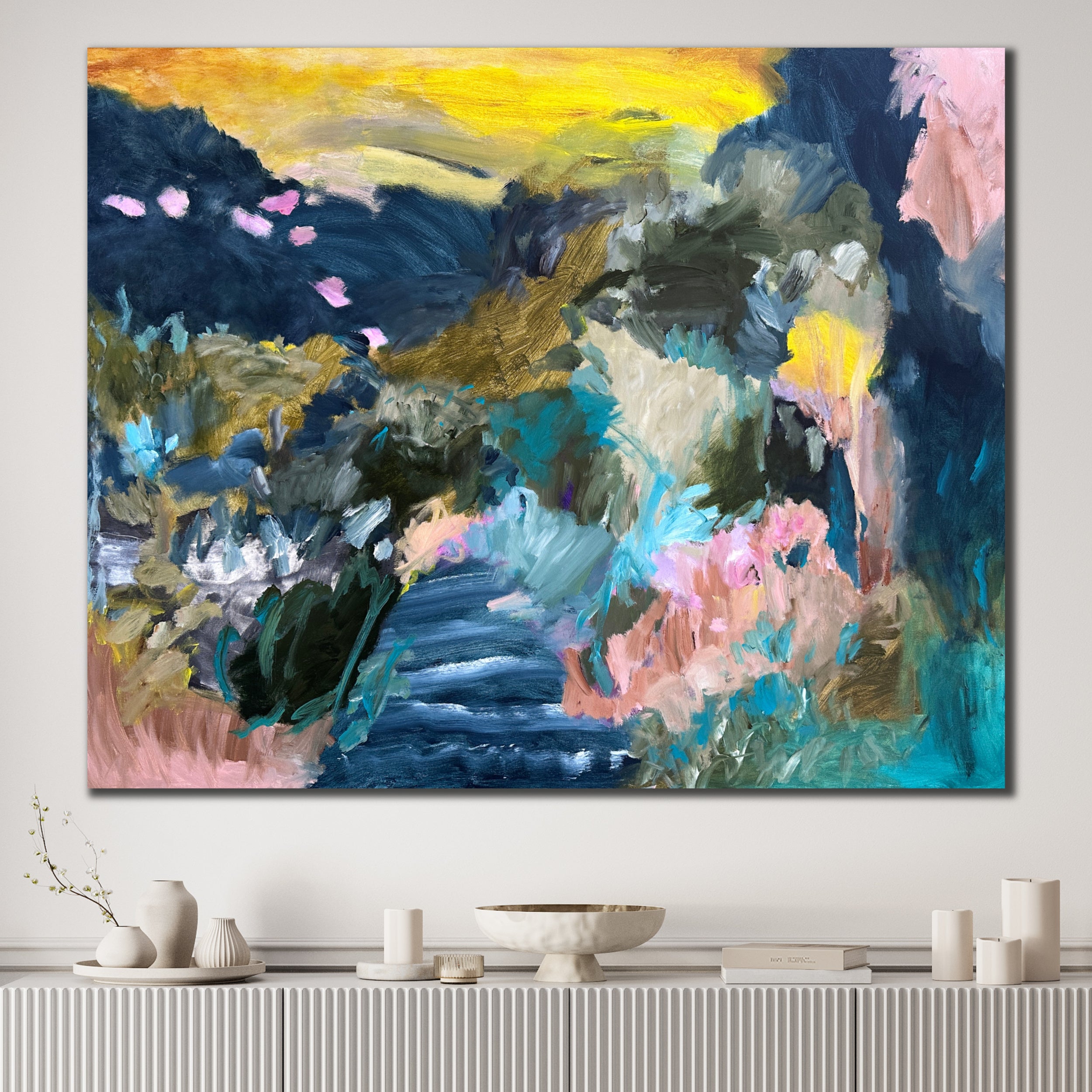 Abstract painting of countryside and water, with vibrant colours on a white wall in modern home