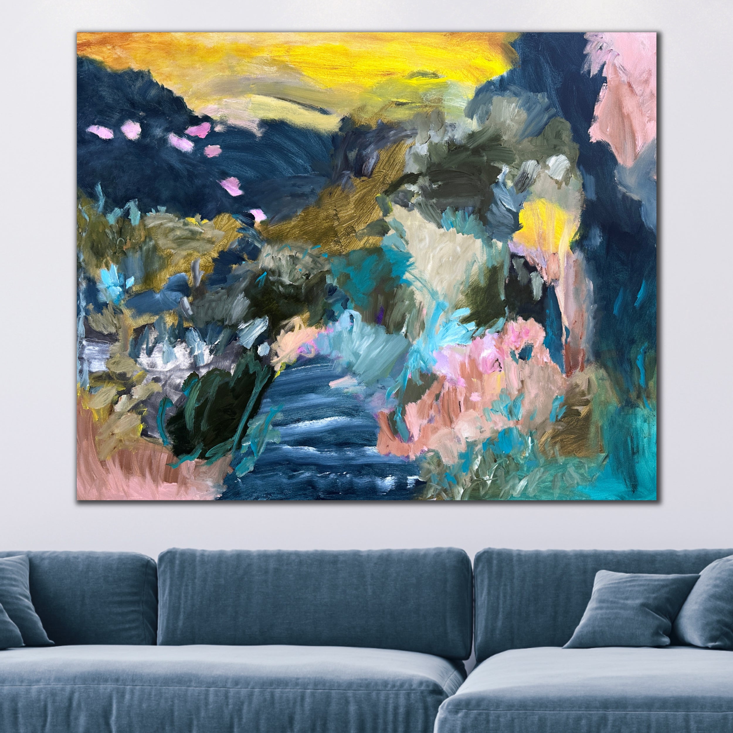 Large abstract painting of a colourful landscape hanging on wall above a sofa