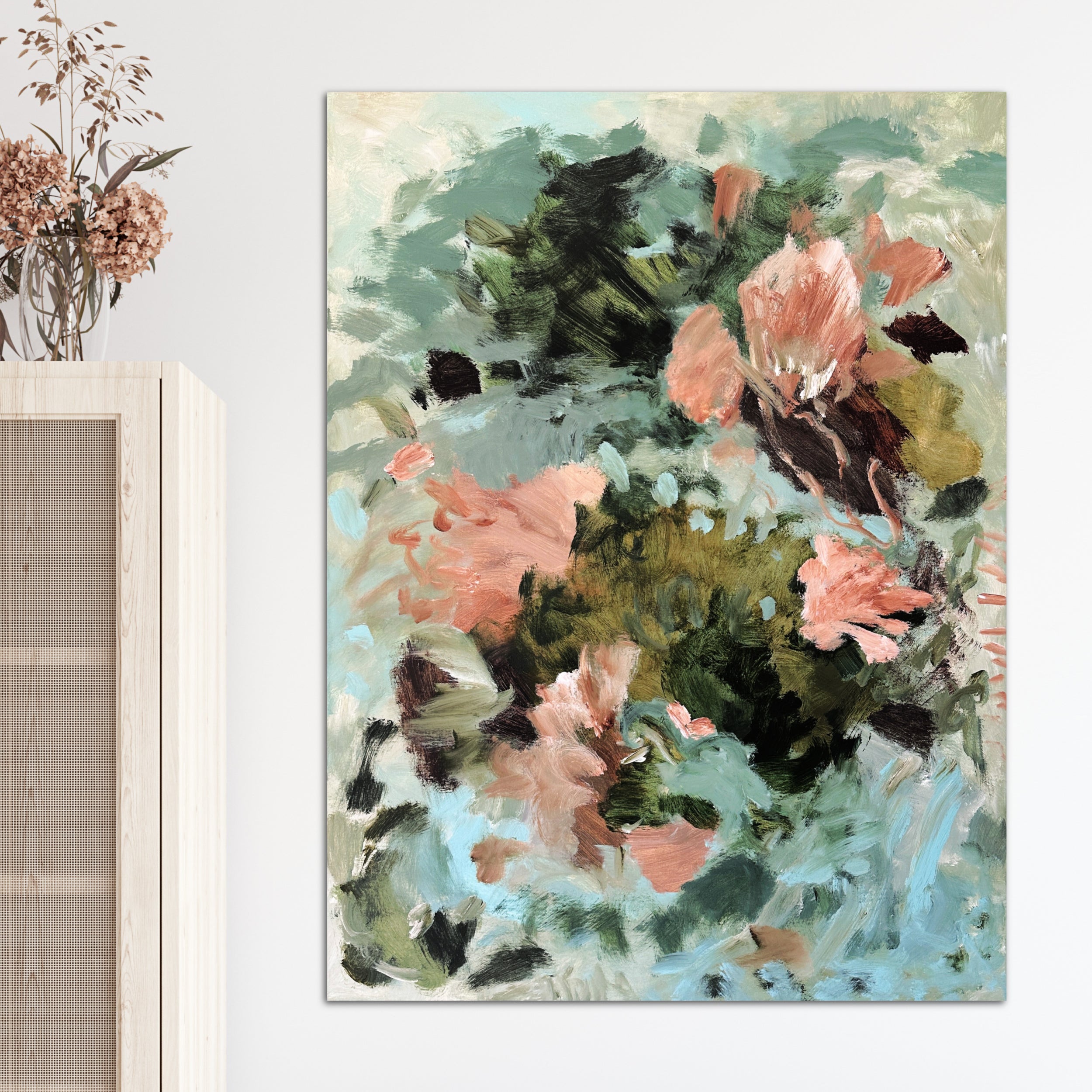 Abstract floral painting in gestural style with terracotta brown, green and light blue tones hanging on wall in room with natural furnishings