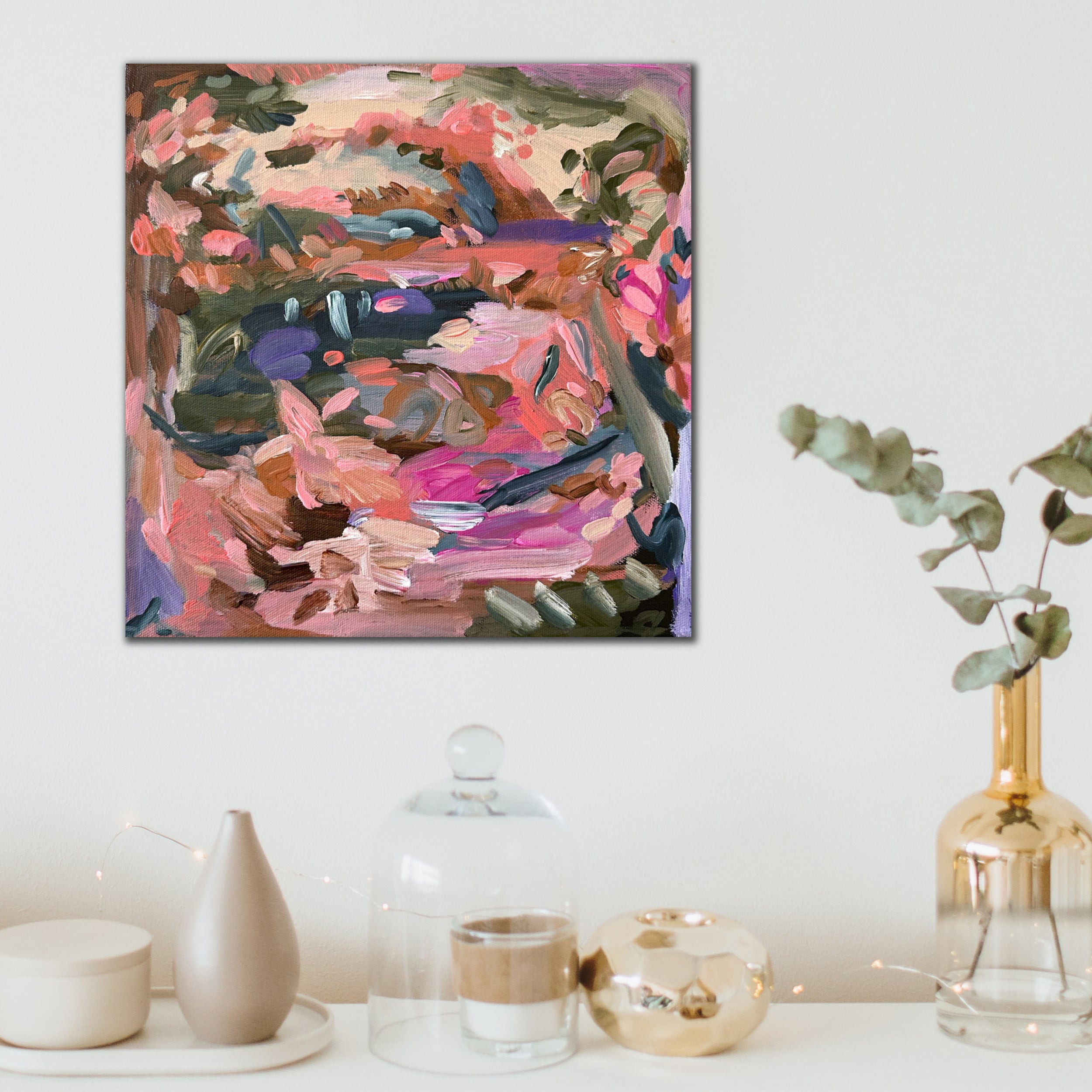 Small square colourful abstract painting of a vivid landscape in pink, green, purple and brown hanging on wall in modern home interior