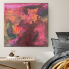 Expressive abstract painting in burgundy, pink, orange and green hanging in bedroom of home interior