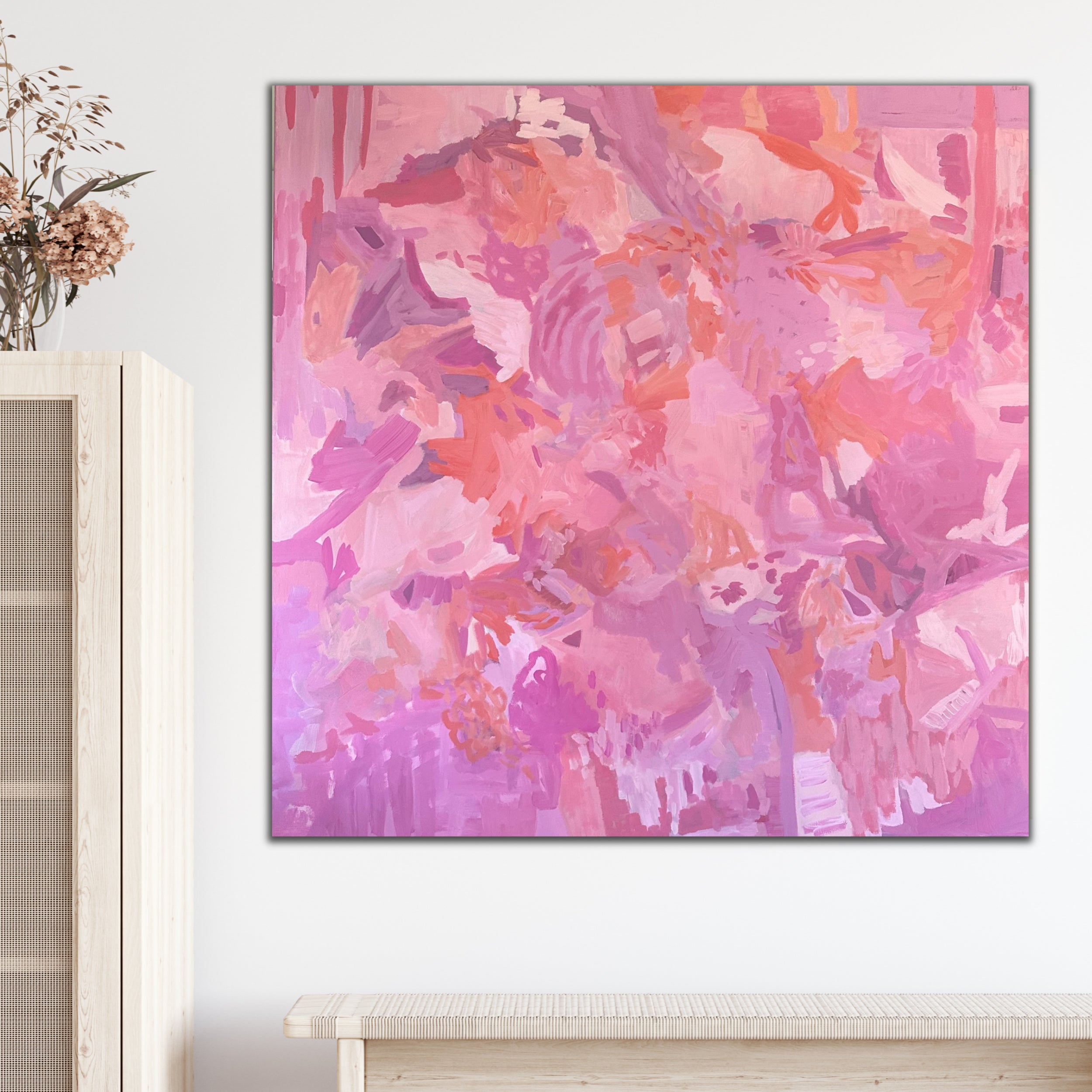 Abstract expressionist painting in pink, salmon and mauve tones hanging in a contemporary interior space with natural timber furnishings