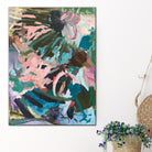 Colourful garden inspired abstract painting hanging on wall in neutral modern interior with plant basket