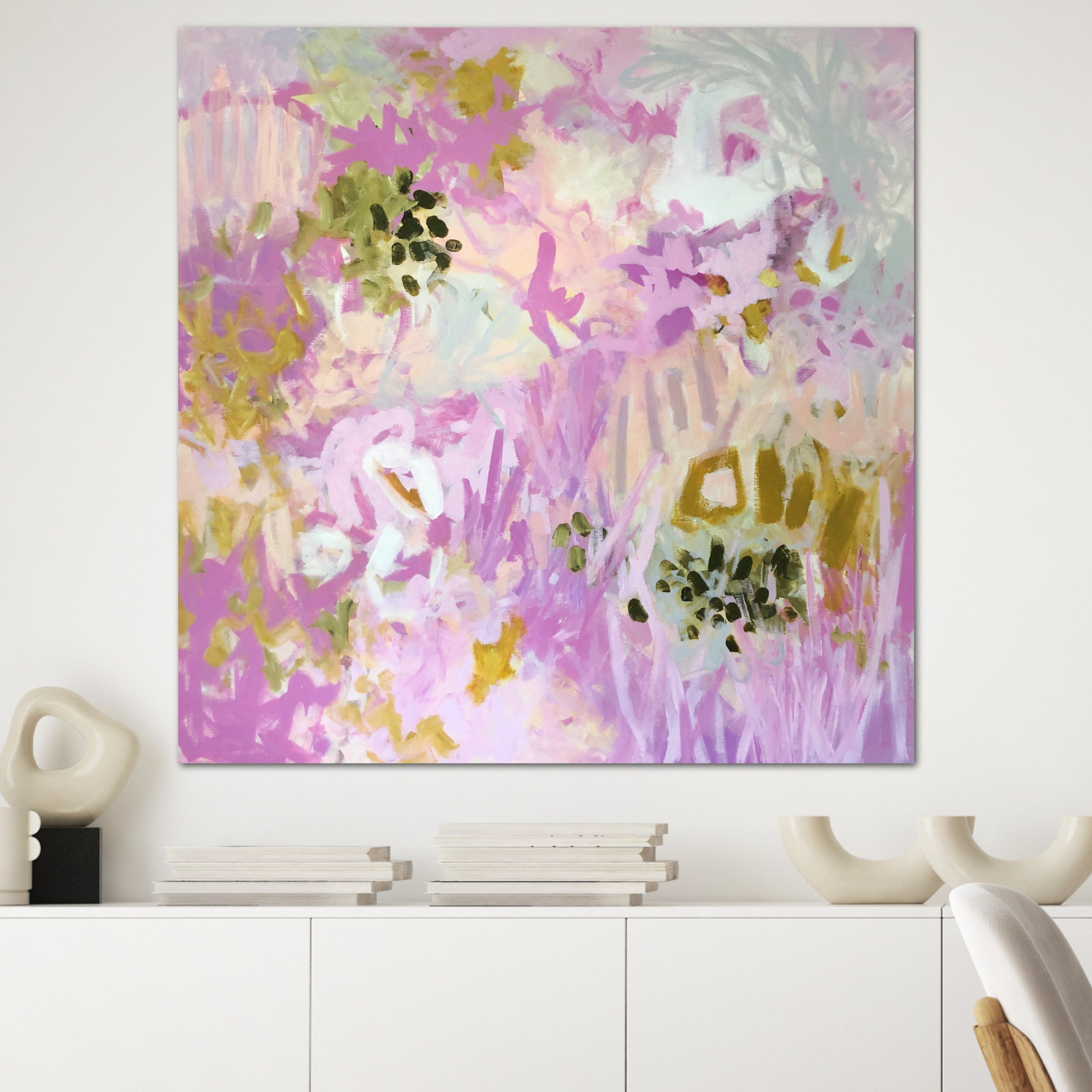 Square, abstract landscape painting with pretty botanical elements hanging on wall in room with neutral, contemporary decor