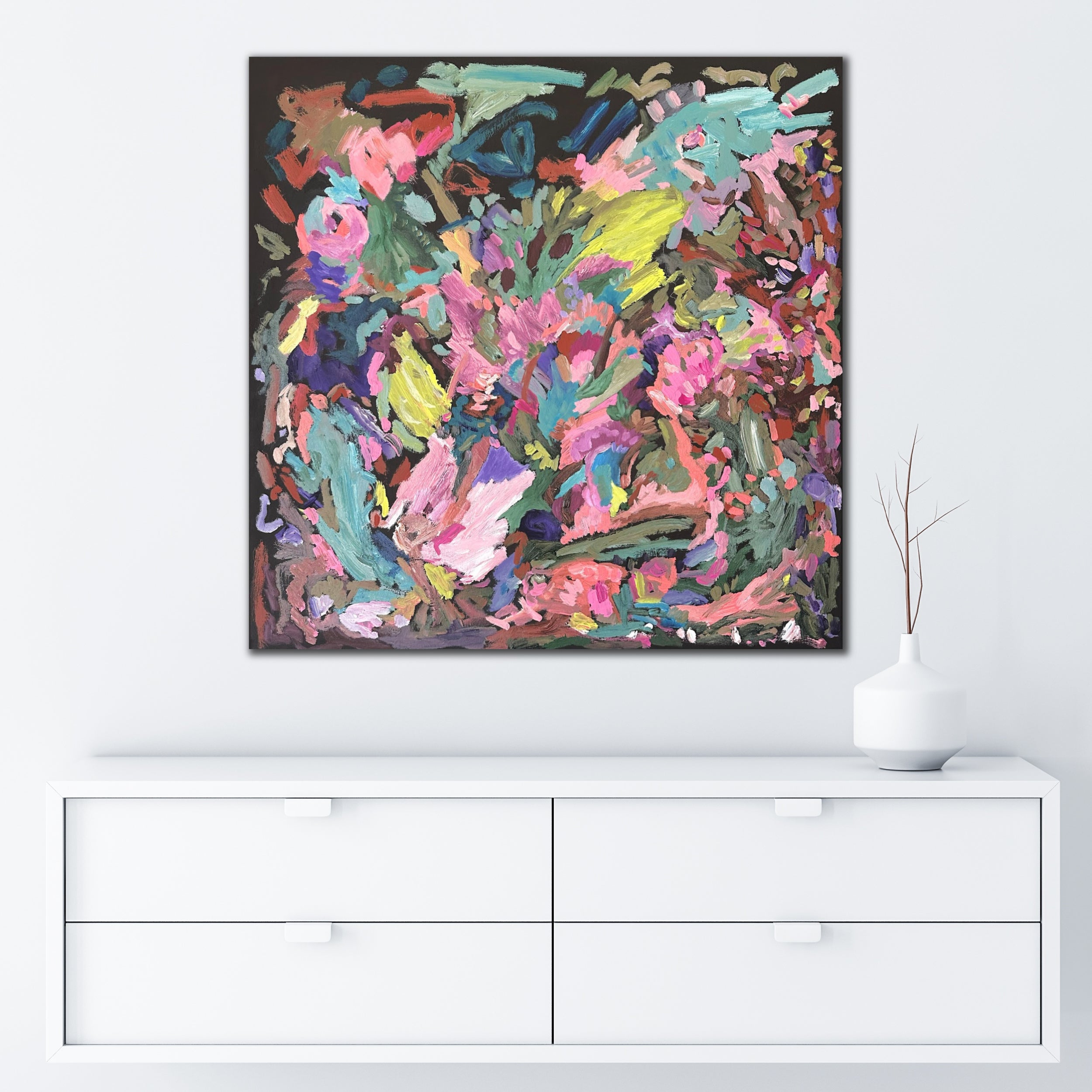 Square abstract painting with botanical influence in bright colours of pink, , green, blue and yellow hanging on wall in minimalist white interior